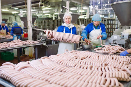 Butchers processing sausages at the meat factory.の写真素材
