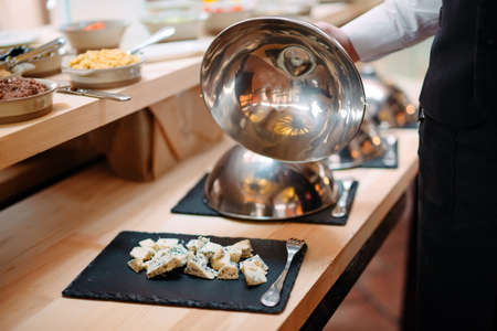 Cutting cheese on a metal bowl with a cap. Breakfast at the Hotel or restaurantの写真素材