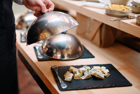 Cutting cheese on a metal bowl with a cap. Breakfast at the Hotel or restaurant.の写真素材