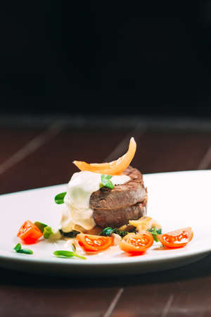 Veal medallions with spinach on a white plate on a wooden backgroundの写真素材