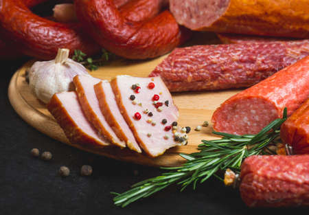 Different types of sausages and meat products on a black background.の写真素材