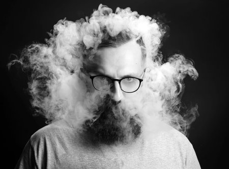 Concept. Smoke enveloped the head man. Portrait of a Bearded, stylish man with smoke. Secondhand...