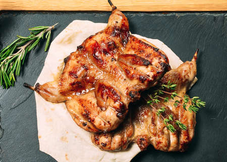 Grilled quails on wooden plate on the tableの写真素材