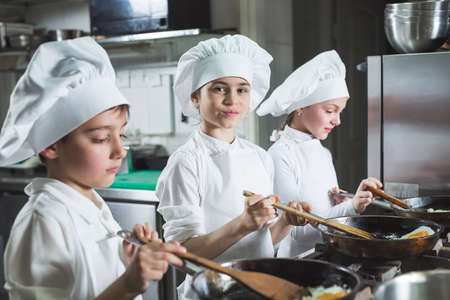 Children cook eggs in the kitchen at the Restaurant.の写真素材