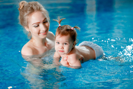 Mom and baby swim in the pool.