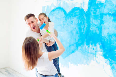 Mother, father and little daughter painting the wall in their new home.の写真素材