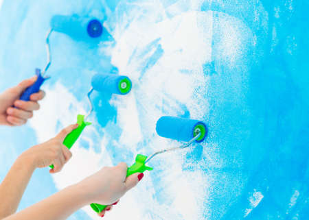 blue color painting wall with roller in hand.の写真素材