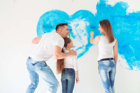 Mother, father and little daughter painting the wall in their new home.の写真素材