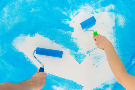 blue color painting wall with roller in hand.の写真素材
