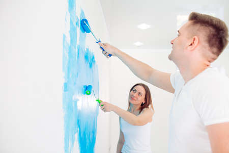 Happy couple painting walls in their new house ready for living together.の写真素材