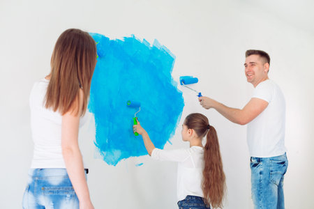 Mother, father and little daughter painting the wall in their new home.