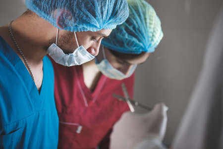 Group of surgeons at work operating in surgical theatre. Resuscitation medicine team wearing protective masksの写真素材