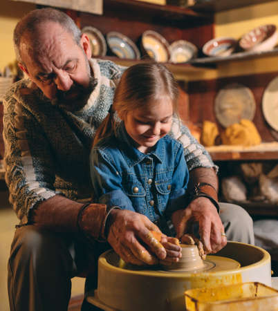 Pottery workshop. Grandpa teaches granddaughter pottery. Clay modelingの写真素材