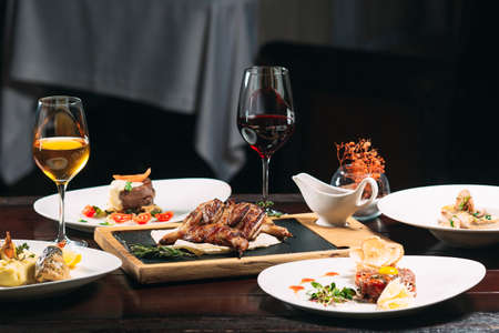Grilled partridge, sea bass, Tartarus. Different dishes on the table in the restaurantの写真素材