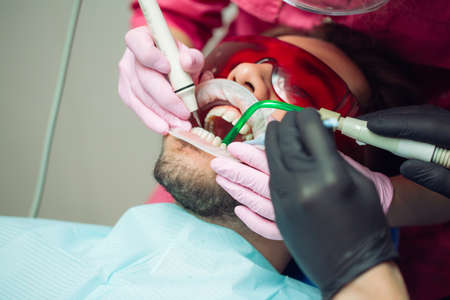 Professional teeth cleaning. Dentist cleans the teeth of a male patient.の写真素材