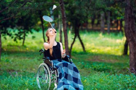 A young disabled girl plays badminton with her younger sister. Interaction of a healthy person with...