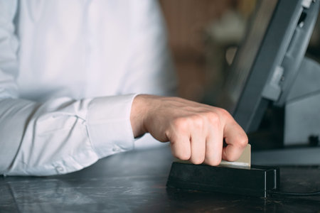 small business, people and service concept - happy man or waiter in apron at counter with cashbox...