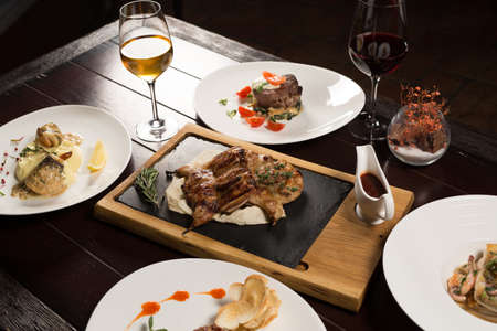 Grilled partridge, sea bass, Tartarus. Different dishes on the table in the restaurant.の写真素材