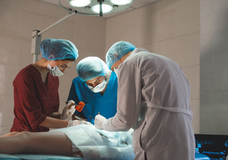 Group of surgeons at work operating in surgical theatre. Resuscitation medicine team wearing...
