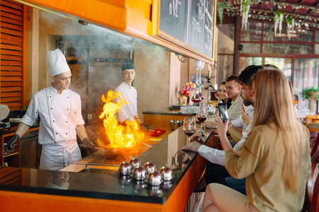 The chef prepares food in front of the visitors in the restaurantの写真素材