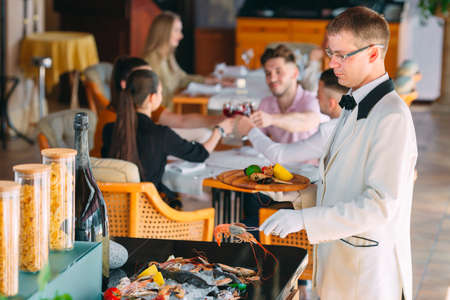 The waiter shifts the seafood on a tray in the restaurant.の写真素材