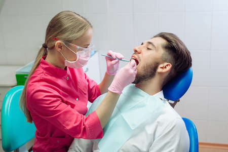 Professional teeth cleaning. Dentist cleans the teeth of a male patient.の写真素材
