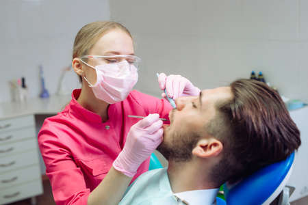 Professional teeth cleaning. Dentist cleans the teeth of a male patient.の写真素材