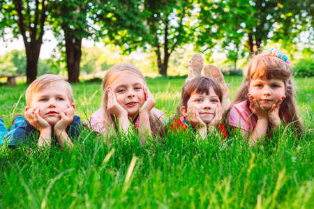A group of children lying on the green grass in the Park. The interaction of the children.の写真素材
