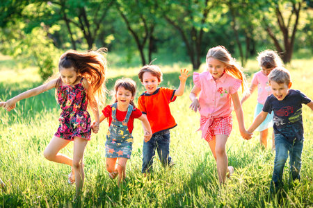 Large group of kids, friends boys and girls running in the park on sunny summer day in casual...
