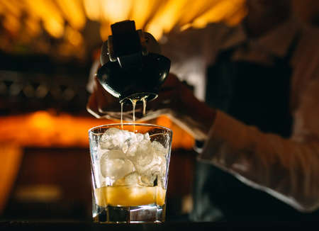 The bartender squeezes citrus juice into a cocktail.の写真素材