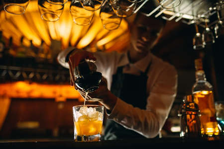 The bartender squeezes citrus juice into a cocktail.の写真素材