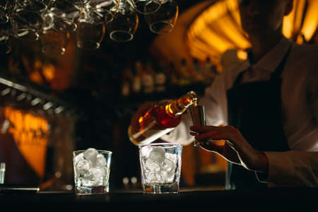 The bartender pours whiskey on the bar.の写真素材