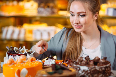 Girl looking at the bakery window with different pieces of cakes.の写真素材