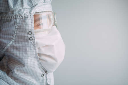 Portrait of a male doctor of European appearance in a medical mask, protective glasses and chemical suit.の写真素材