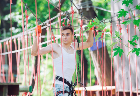 Man spend their leisure time in a ropes course. Man engaged in rope park.