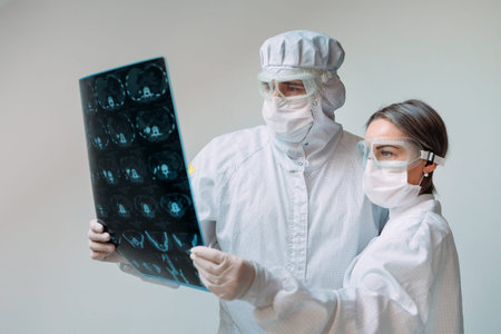 Doctors standing on white background examine x-ray for pneumonia of a Covid-19 patient in the...
