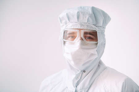 Portrait of a male doctor of European appearance in a medical mask, protective glasses and chemical suit.の写真素材