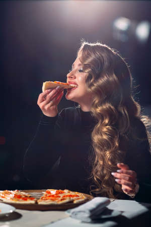 Young beautiful girl alone eating pizza in a restaurant.の写真素材