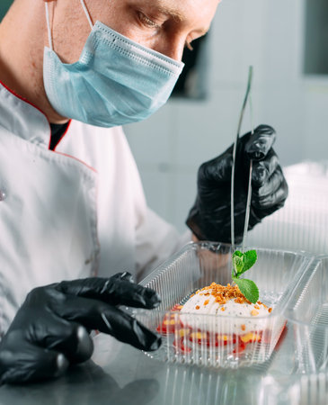 Food delivery in the restaurant. The chef prepares food in the restaurant and packs it in disposable...