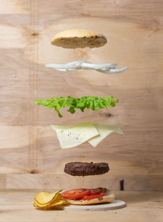 Flying Burger Ingredients Isolated On Wood Backgroundの写真素材