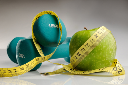 healthy apple, measuring tape and dumbbells for healthy livingの写真素材