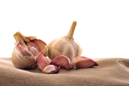two heads of garlic on brown fabric  isolated background