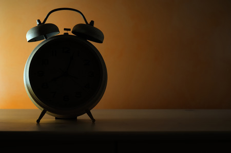 bedside vintage alarm clock in backlitの写真素材