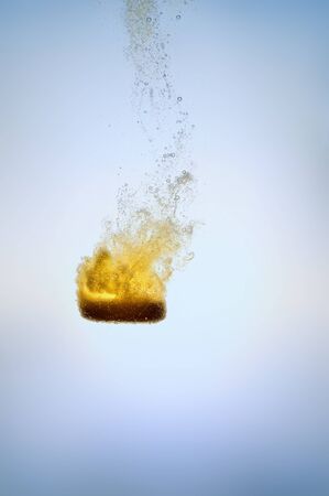 Effervescent orange tablet falling blue isolatedの写真素材