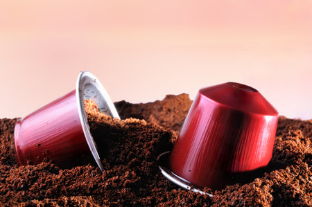 capsules for espresso coffee machine on heap of ground coffee and brown isolated backgroundのeditorial素材