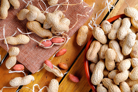 Group of healthy peanuts shelled and unshelled exposed on a wooden table in the field top viewの写真素材