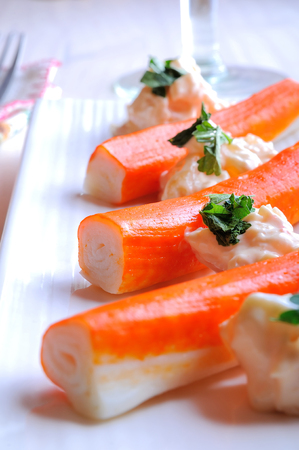 Surimi sticks with sauce on a white plate on a white wooden table closeupの写真素材