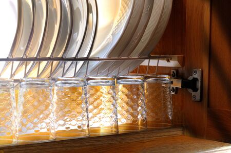 Clean dishes and glasses in the draining of a kitchen cabinet brown houseの写真素材