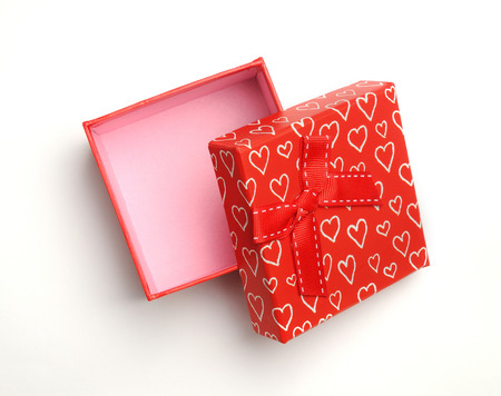 Decorative open square red gift box with red ribbon and white painted hearts. Top view. White isolated background.の写真素材