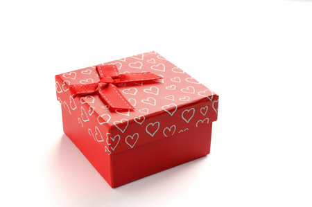 Decorative square red gift box with red ribbon and white painted hearts. Front view. White isolated background.の写真素材